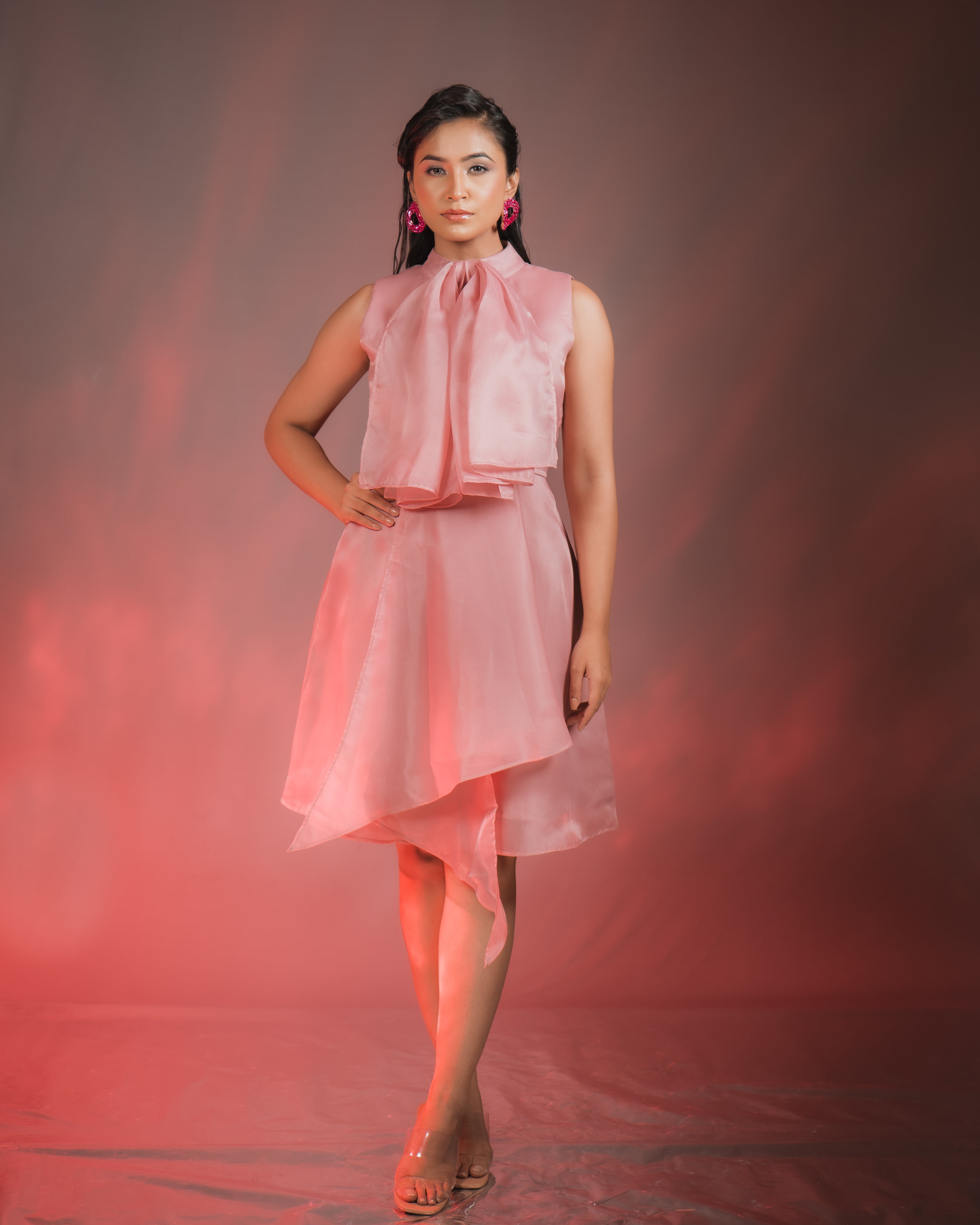Model wearing an ORGANZA BOW DRESS in pink, featuring a bow detail and zip closure at the back.